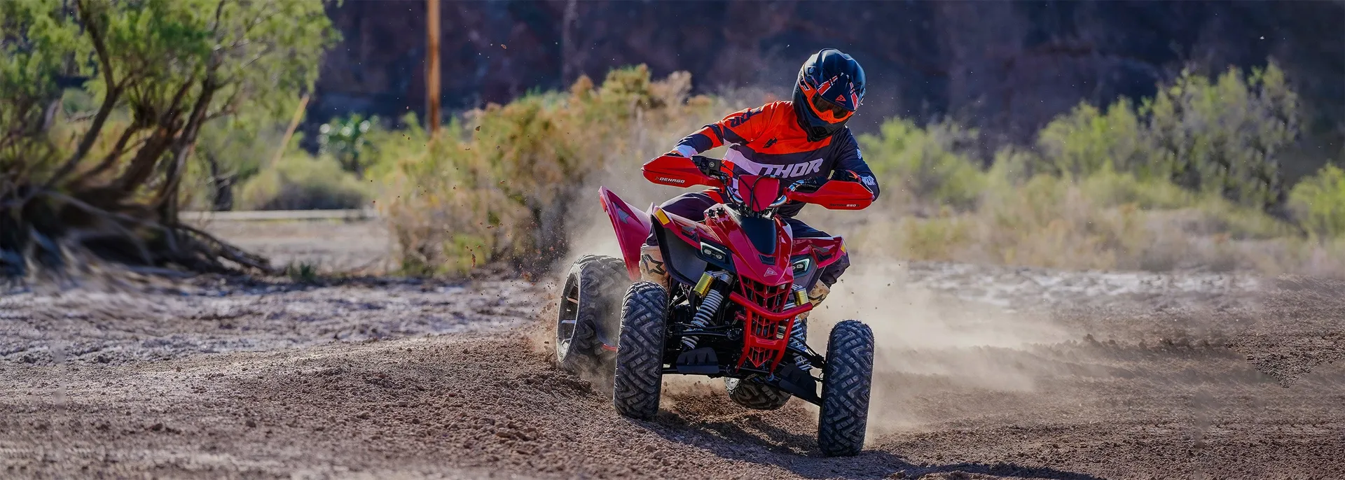 Denago youth ATV rider roosting dust on an off-road trail